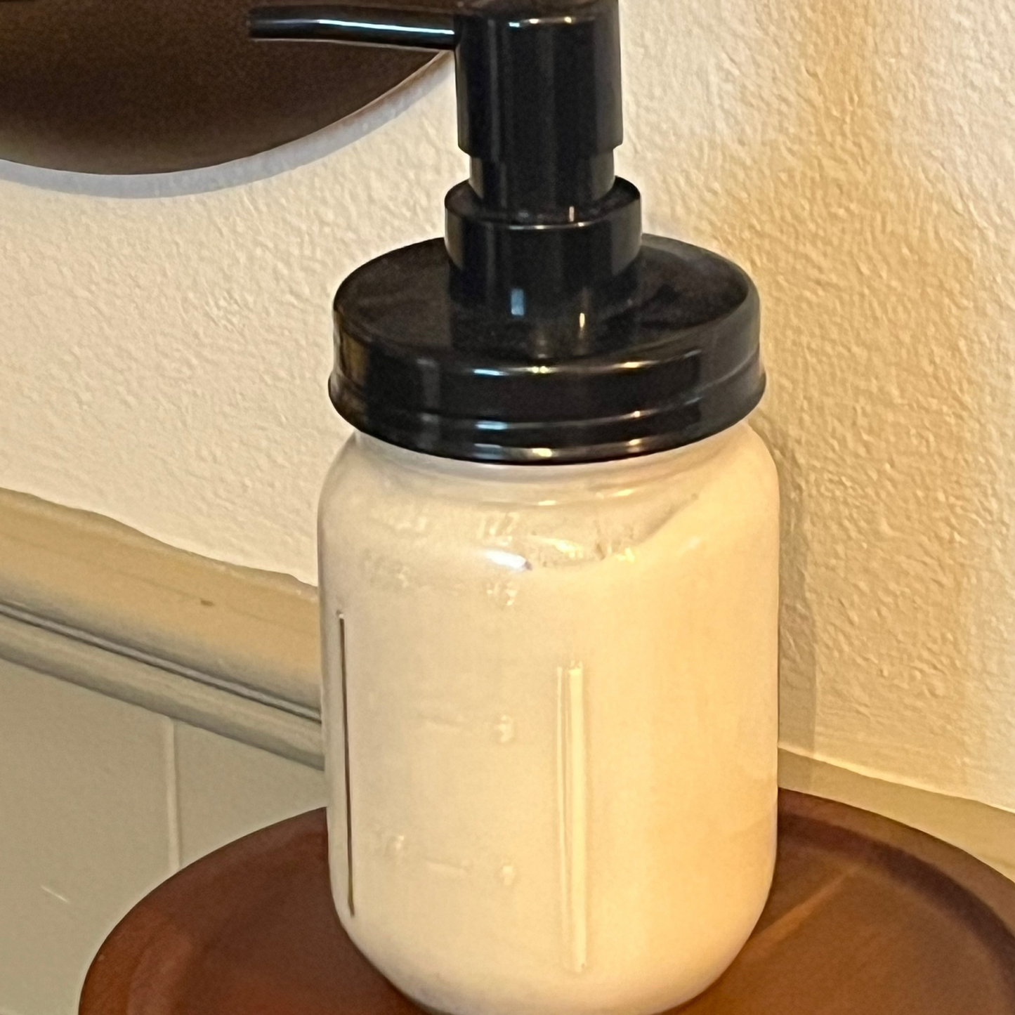Glass jar with black pump dispenser on a wooden surface