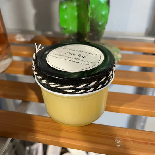 Small container with a black lid on a wooden surface, featuring a cactus plant in the background.