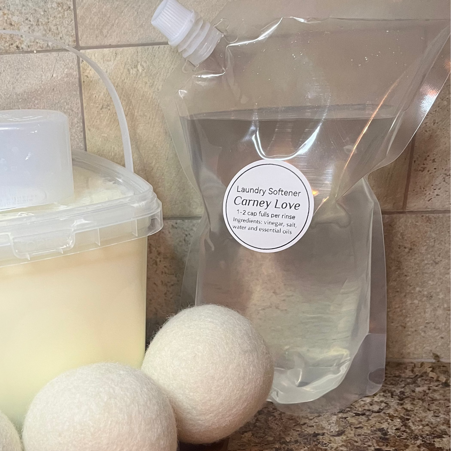 Bucket of detergent, plastic bag, and three white balls on a countertop.